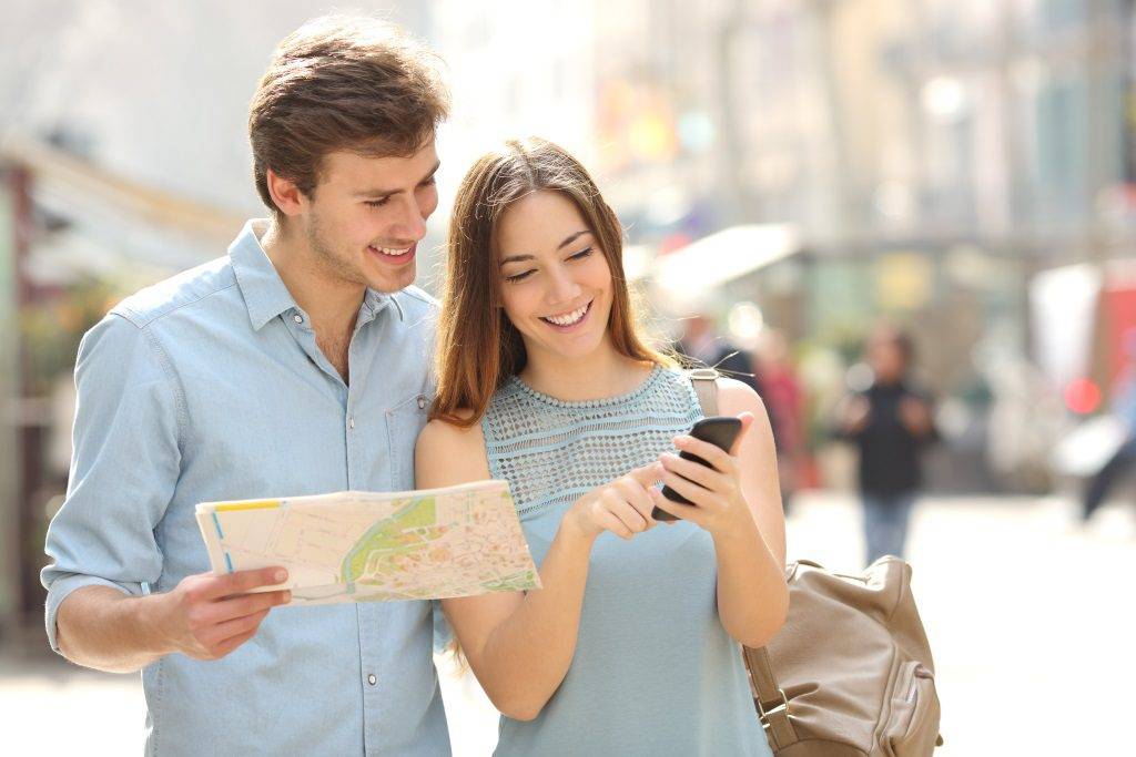 Couple of tourists consulting a city guide and smartphone gps
